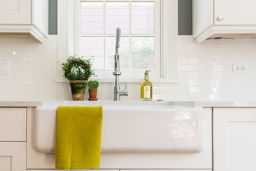 Inspiration for a large transitional l-shaped medium tone wood floor and brown floor open concept kitchen remodel in Chicago with a farmhouse sink, recessed-panel cabinets, white cabinets, quartz countertops, white backsplash, subway tile backsplash, stainless steel appliances, an island and white countertops