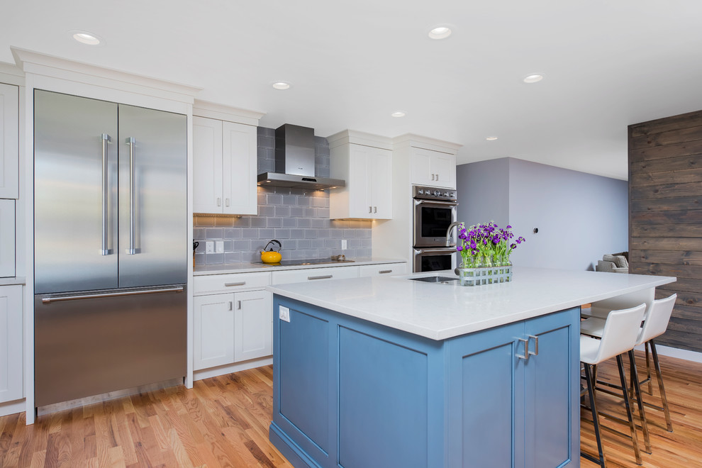 Large transitional u-shaped light wood floor enclosed kitchen photo in Denver with a farmhouse sink, shaker cabinets, white cabinets, quartz countertops, gray backsplash, ceramic backsplash, stainless steel appliances and an island