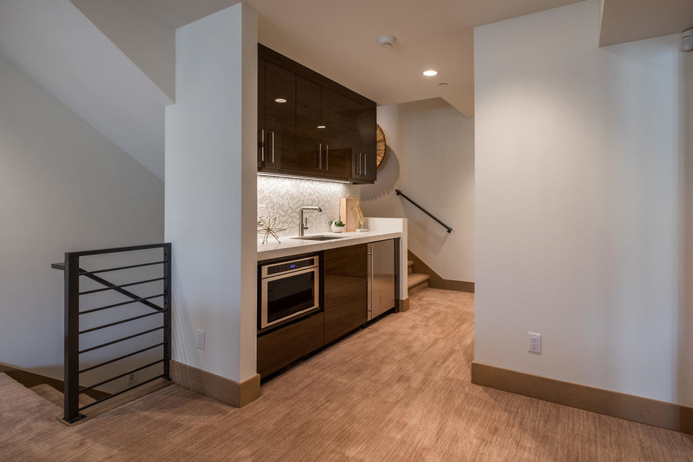 Small transitional single-wall wet bar in Salt Lake City with an undermount sink, flat-panel cabinets, brown cabinets, quartz benchtops, white splashback, glass tile splashback, carpet, brown floor and white benchtop.