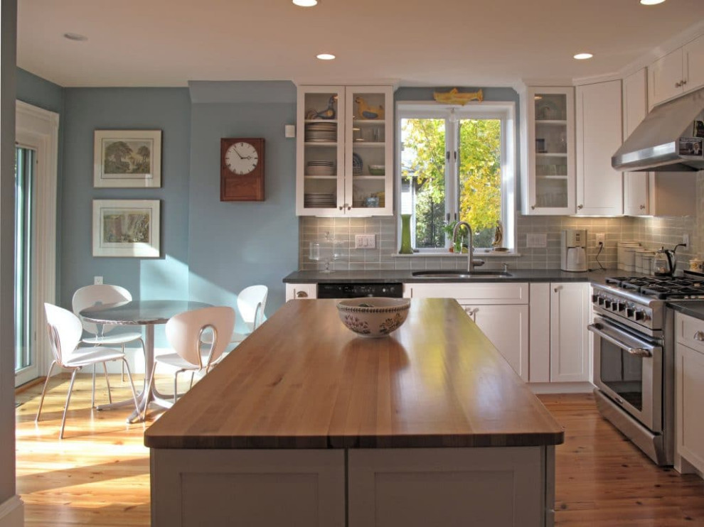 Inspiration for an eclectic medium tone wood floor kitchen remodel with glass-front cabinets, white cabinets, granite countertops, gray backsplash, ceramic backsplash, stainless steel appliances, an island and gray countertops