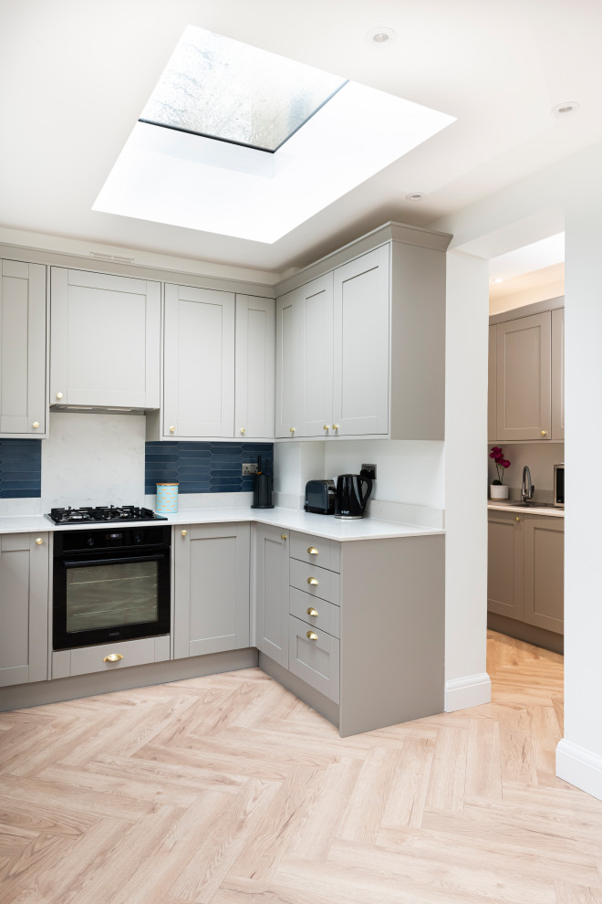 Medium sized modern grey and white u-shaped open plan kitchen in London with a single-bowl sink, shaker cabinets, grey cabinets, white splashback, no island and white worktops.