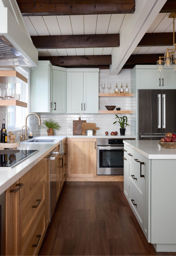 Mid-sized transitional l-shaped medium tone wood floor, brown floor and exposed beam eat-in kitchen photo with a single-bowl sink, shaker cabinets, medium tone wood cabinets, quartz countertops, white backsplash, subway tile backsplash, stainless steel appliances, an island and white countertops