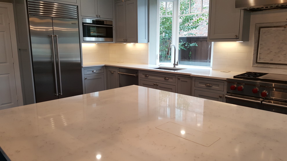 Inspiration for a mid-sized transitional l-shaped open plan kitchen in Dallas with an undermount sink, shaker cabinets, grey cabinets, quartz benchtops, white splashback, marble splashback, stainless steel appliances, medium hardwood floors, with island and brown floor.