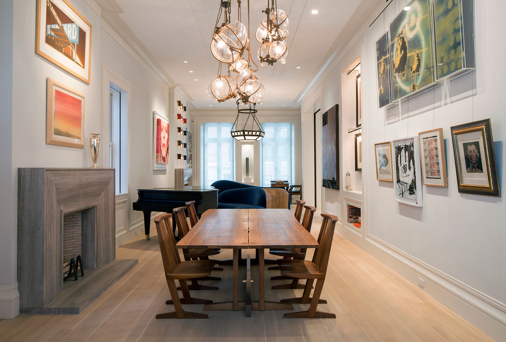Example of a large trendy light wood floor great room design in New York with white walls, a standard fireplace and a wood fireplace surround