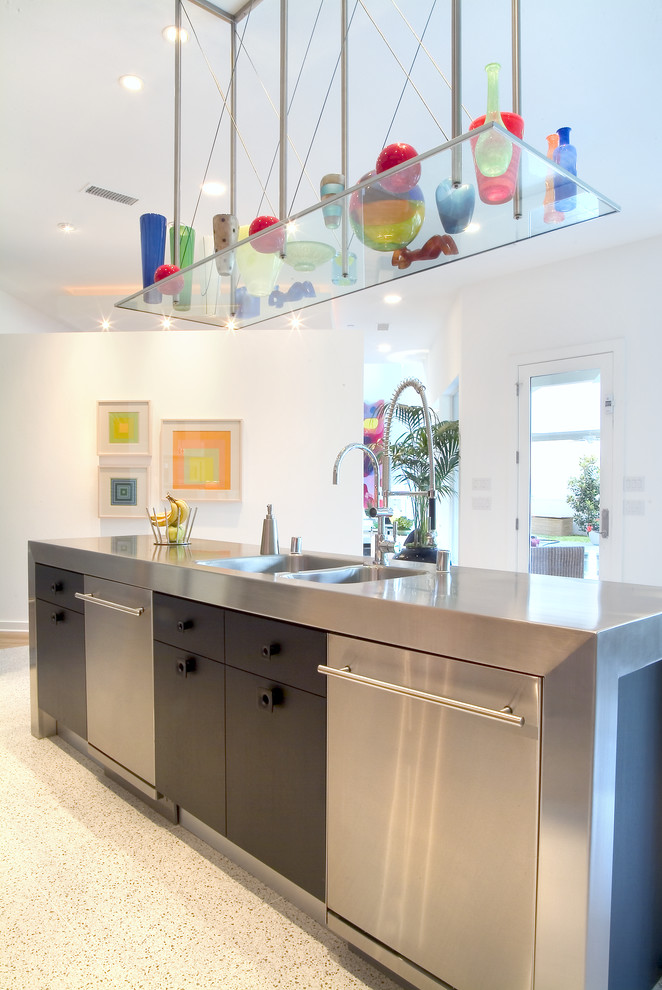 Photo of a large contemporary l-shaped eat-in kitchen in Dallas with a double-bowl sink, flat-panel cabinets, light wood cabinets, stainless steel benchtops, orange splashback, glass sheet splashback, stainless steel appliances and with island.