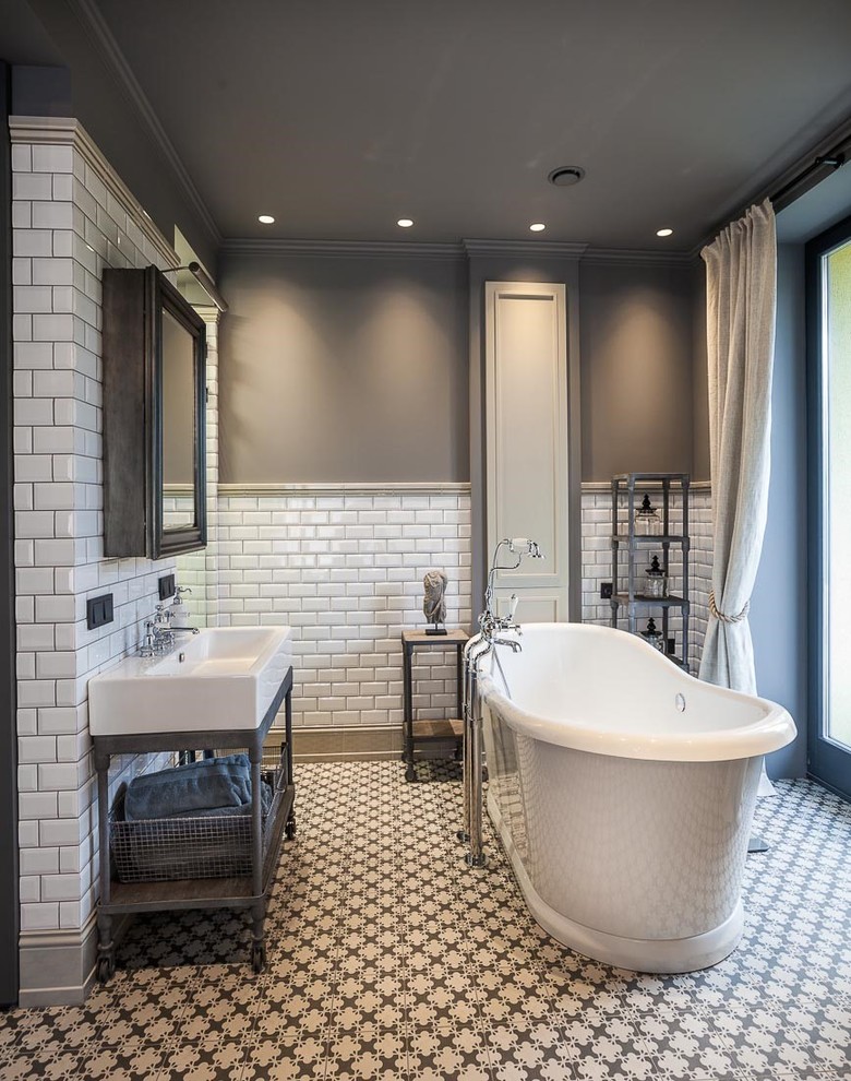Photo of a mid-sized industrial bathroom in London with furniture-like cabinets, grey cabinets, a freestanding tub, a curbless shower, gray tile, subway tile, grey walls, porcelain floors and a wall-mount sink.