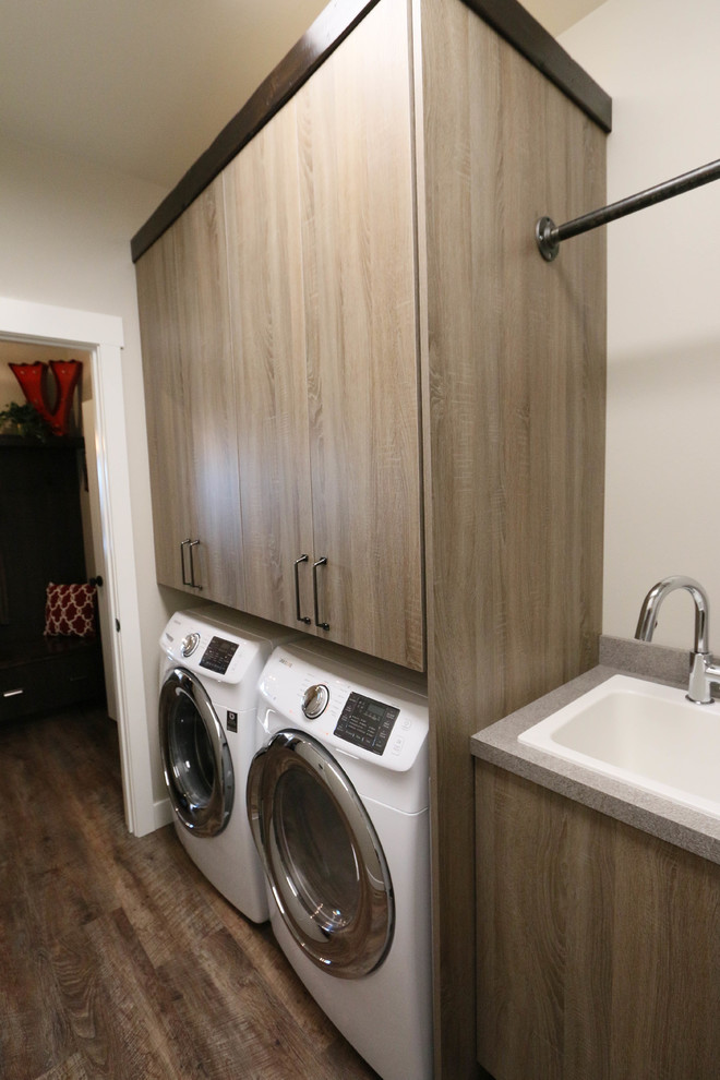 This is an example of an industrial l-shaped laundry room in Little Rock with flat-panel cabinets, grey cabinets, laminate benchtops and a side-by-side washer and dryer.