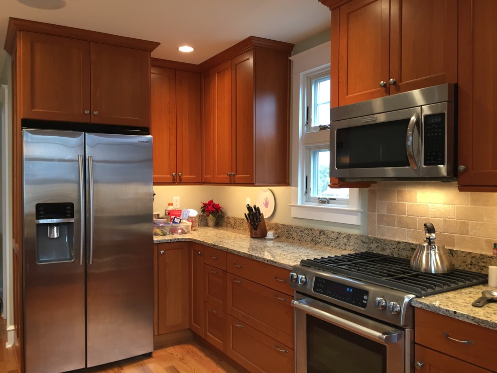 Inspiration for a mid-sized traditional l-shaped eat-in kitchen in Philadelphia with an undermount sink, shaker cabinets, medium wood cabinets, granite benchtops, beige splashback, stone tile splashback, stainless steel appliances, medium hardwood floors and a peninsula.