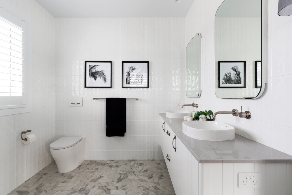 Idéer för mellanstora maritima grått en-suite badrum, med luckor med infälld panel, vita skåp, en öppen dusch, en vägghängd toalettstol, vit kakel, porslinskakel, vita väggar, klinkergolv i keramik, ett piedestal handfat, granitbänkskiva, beiget golv och med dusch som är öppen