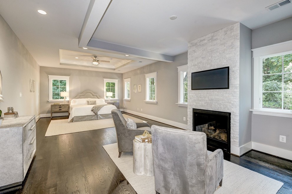 This is an example of an expansive contemporary master bedroom in DC Metro with grey walls, dark hardwood floors, a standard fireplace, a stone fireplace surround and brown floor.