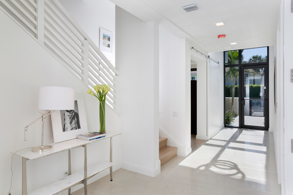 This is an example of a contemporary entry hall in Miami with white walls, a single front door, a glass front door and beige floor.