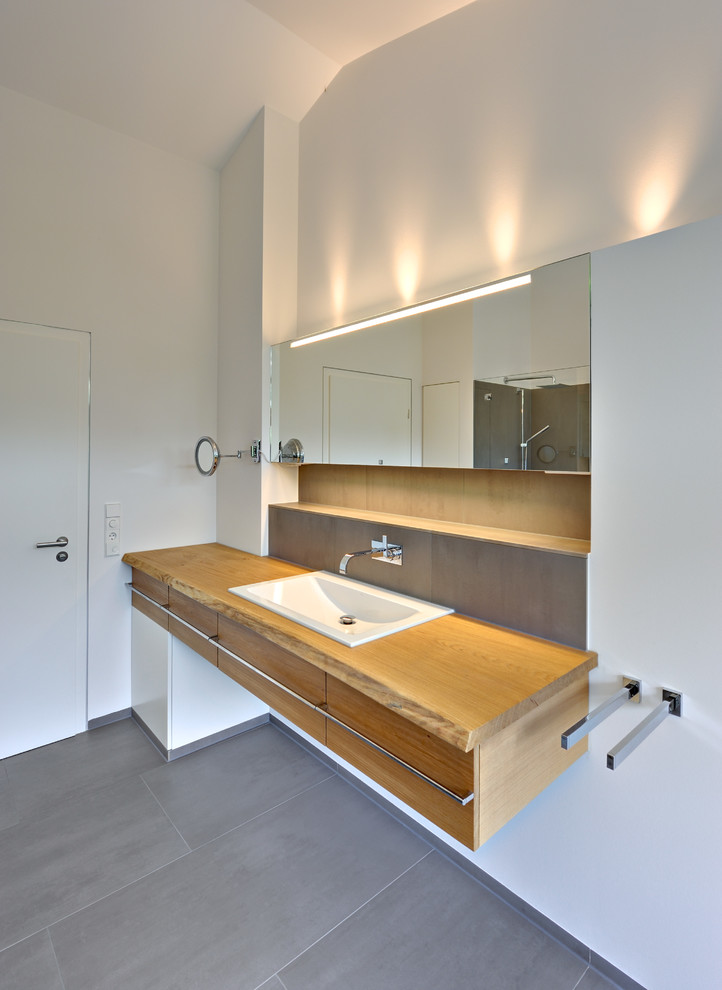 Design ideas for a large contemporary bathroom in Bremen with flat-panel cabinets, medium wood cabinets, white walls, slate floors, a drop-in sink, wood benchtops and brown benchtops.