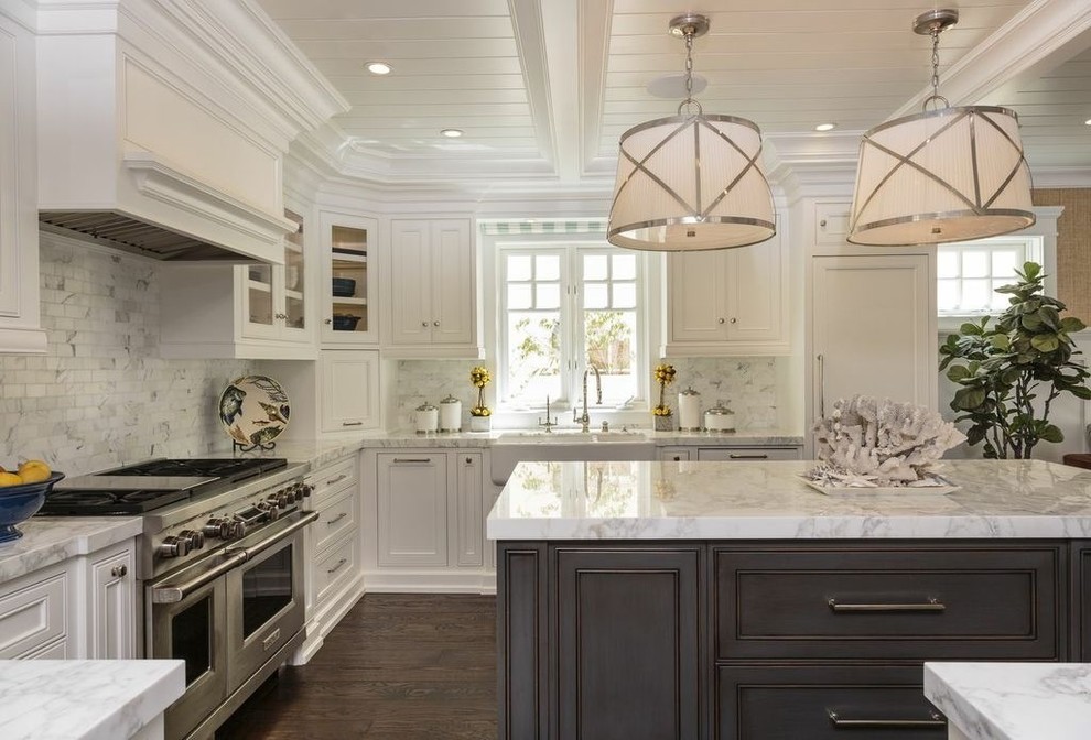 Beach style kitchen in Orange County with a farmhouse sink, recessed-panel cabinets, white cabinets, white splashback, stainless steel appliances, dark hardwood floors and with island.