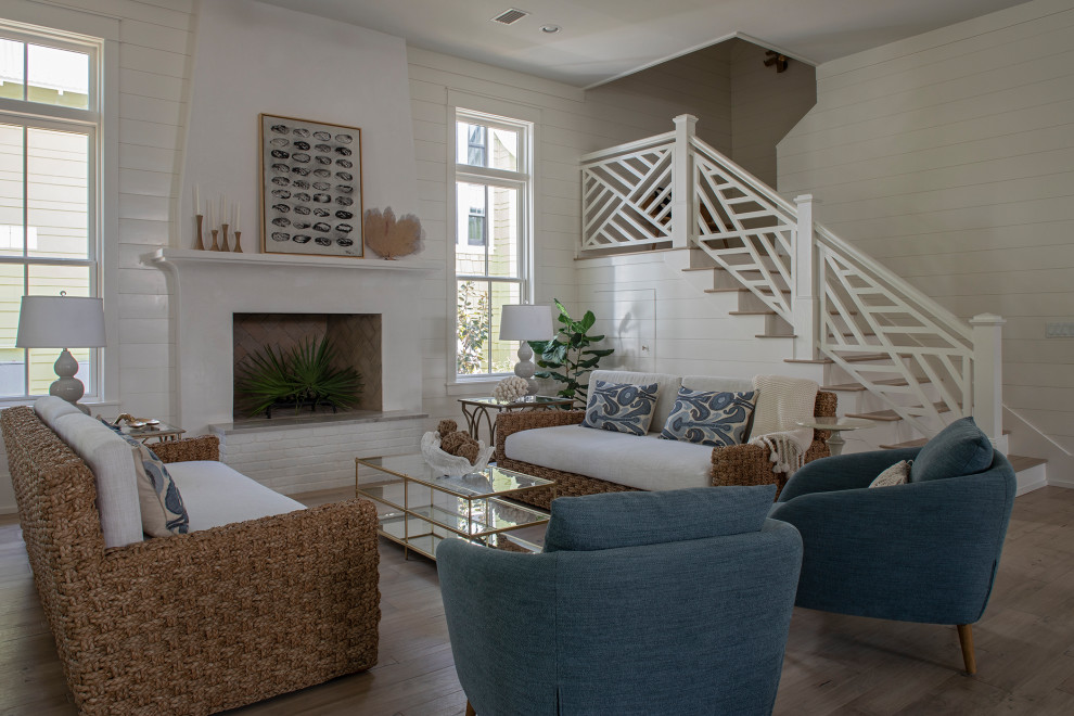 Inspiration for a mid-sized beach style open concept living room in Other with white walls, light hardwood floors, a standard fireplace, a plaster fireplace surround, no tv, beige floor and planked wall panelling.
