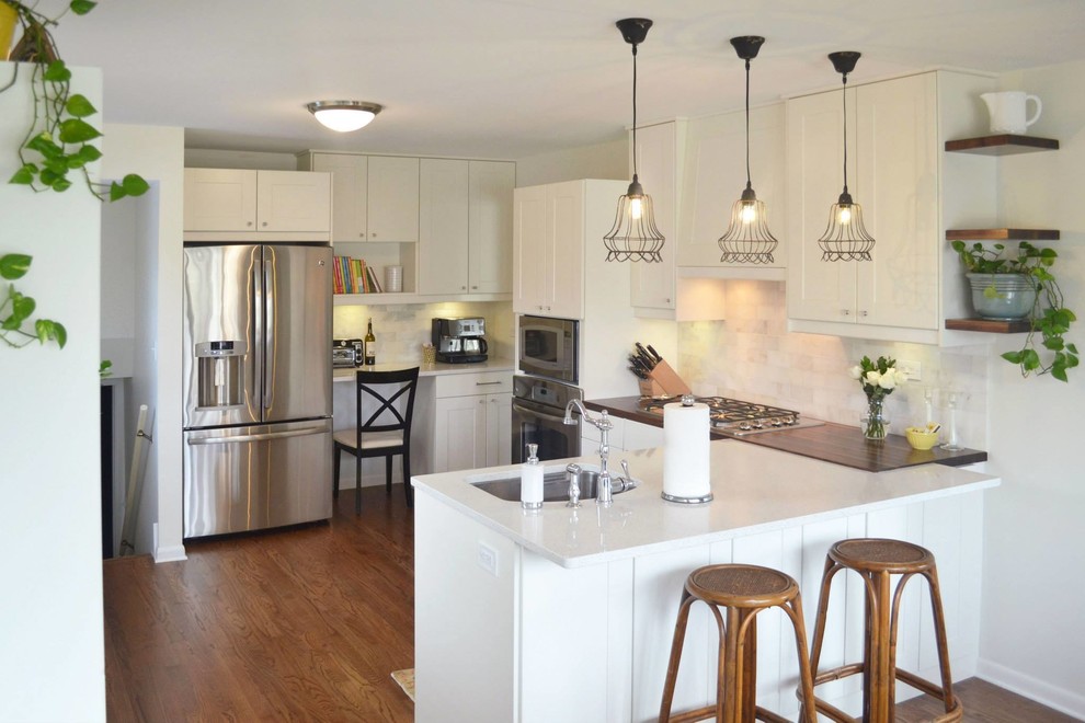 Mid-sized transitional u-shaped medium tone wood floor and brown floor eat-in kitchen photo with shaker cabinets, white cabinets, white backsplash, a peninsula, quartzite countertops, an undermount sink, stone tile backsplash and stainless steel appliances