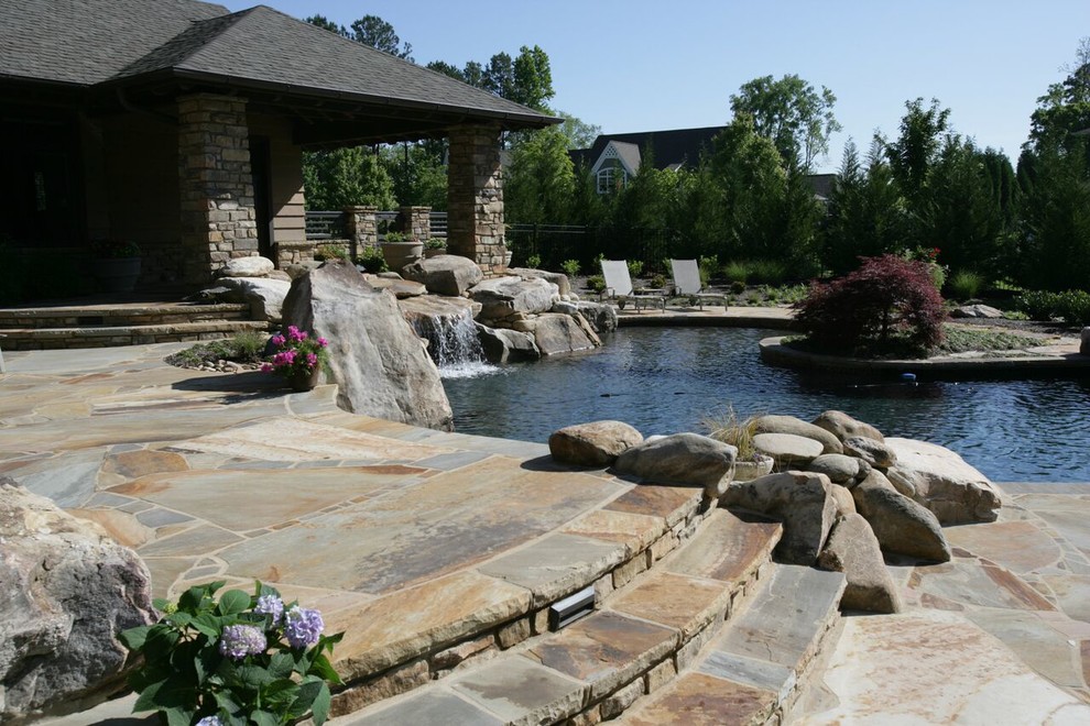 Design ideas for a large arts and crafts backyard custom-shaped lap pool in Other with a hot tub and natural stone pavers.
