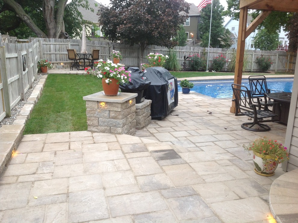 This is an example of a mid-sized traditional backyard patio in Other with stamped concrete and a roof extension.