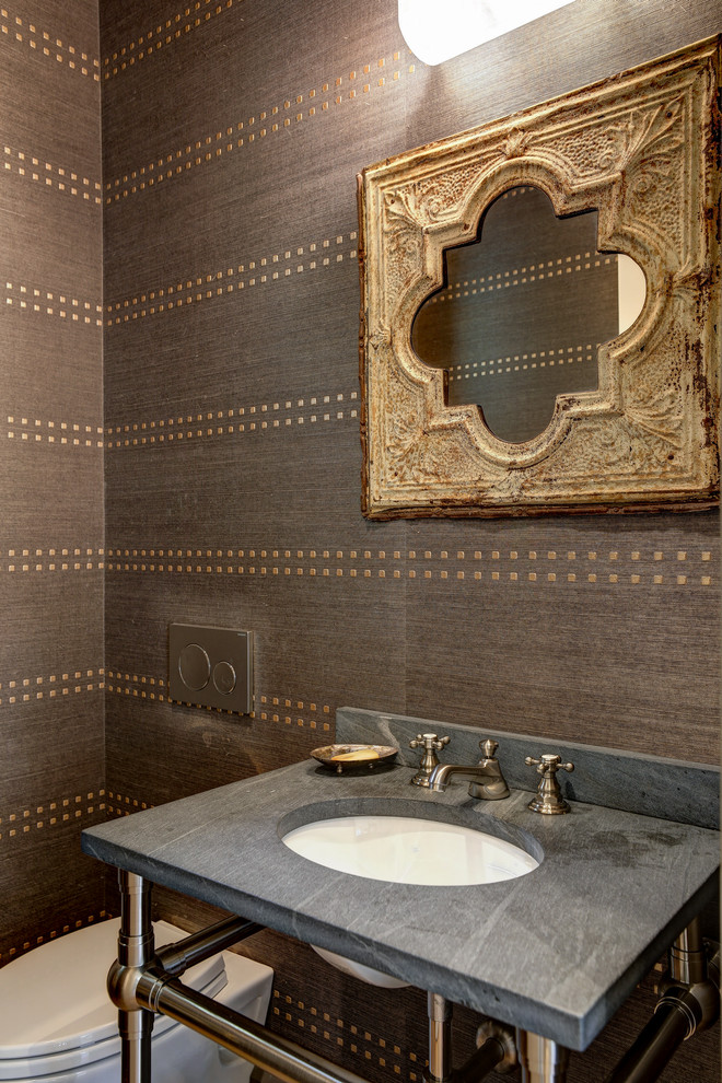 Inspiration for a small transitional powder room in San Francisco with a wall-mount toilet, brown walls, light hardwood floors, a drop-in sink, soapstone benchtops, brown floor and black benchtops.