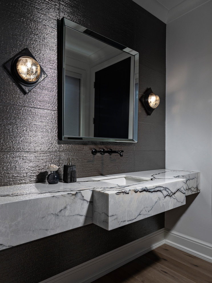 Inspiration for a large modern powder room in Detroit with white cabinets, a one-piece toilet, gray tile, porcelain tile, grey walls, light hardwood floors, an undermount sink, marble benchtops, brown floor, white benchtops and a floating vanity.