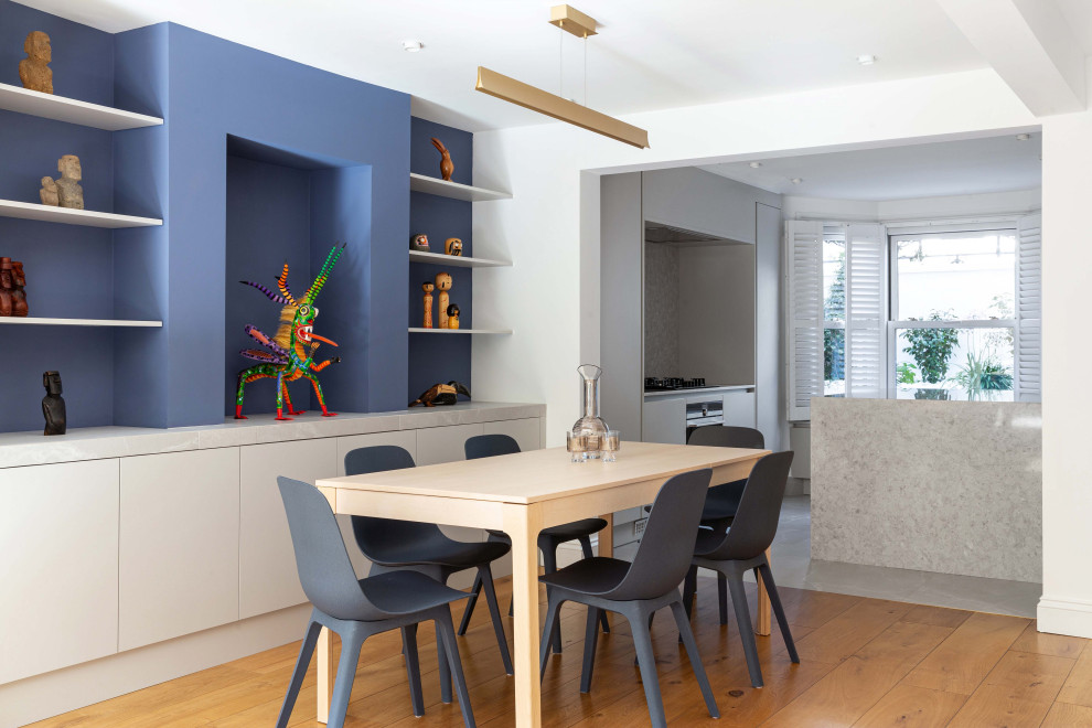 Exemple d'une grande salle à manger ouverte sur le salon tendance avec un mur bleu, un sol en bois brun et éclairage.