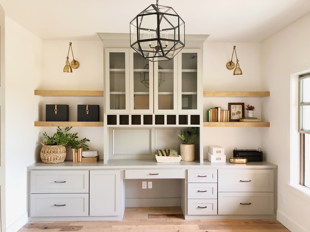 Inspiration for a mid-sized transitional study room in Oklahoma City with white walls, light hardwood floors, no fireplace, a built-in desk and brown floor.