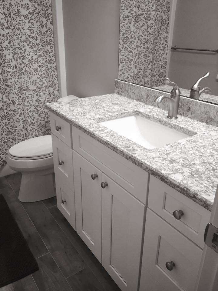 Example of a mid-sized transitional 3/4 porcelain tile and gray floor alcove bathtub design with recessed-panel cabinets, black cabinets, gray walls, an undermount sink and granite countertops