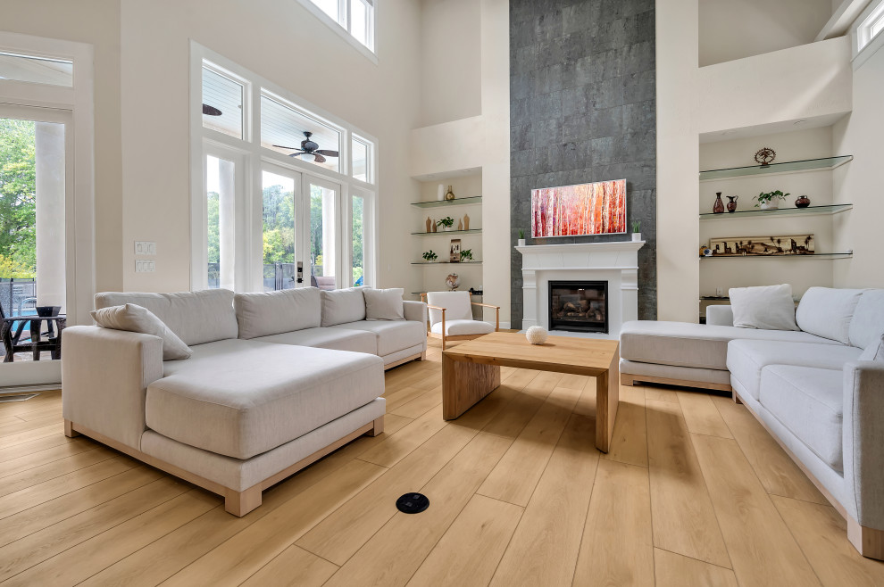 This is an example of a large modern formal open concept living room in Raleigh with beige walls, vinyl floors, a standard fireplace, a concrete fireplace surround, a wall-mounted tv, beige floor and vaulted.