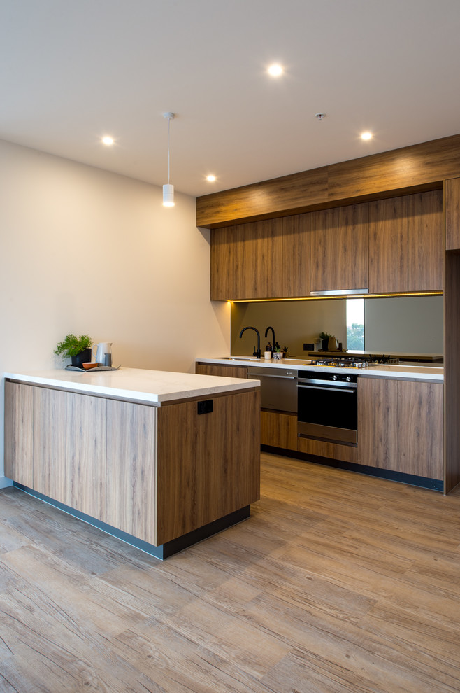 Design ideas for a small contemporary galley open plan kitchen in Melbourne with a single-bowl sink, beaded inset cabinets, brown cabinets, quartz benchtops, metallic splashback, mirror splashback, stainless steel appliances, vinyl floors and with island.