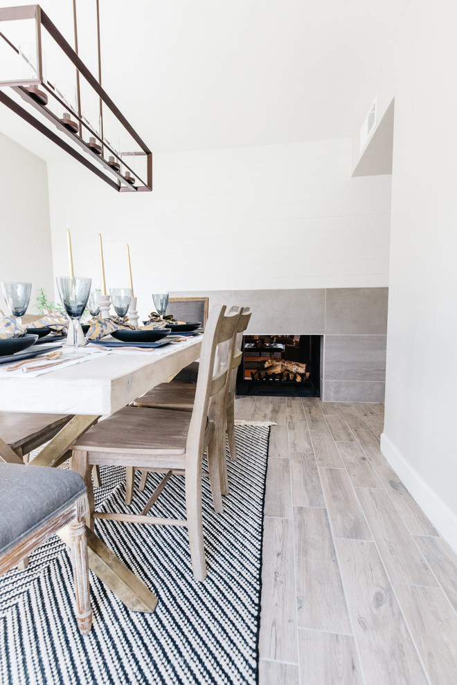 Photo of a mid-sized transitional separate dining room in Phoenix with grey walls, porcelain floors, a two-sided fireplace, a tile fireplace surround and grey floor.