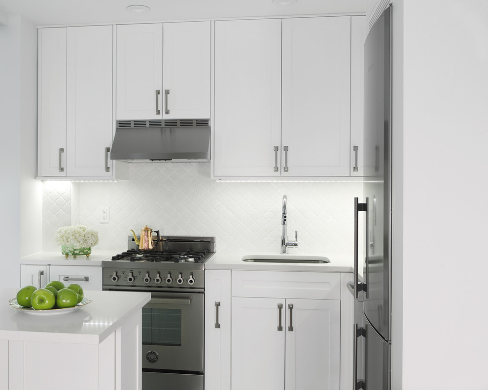 Photo of a small traditional l-shaped eat-in kitchen in New York with an undermount sink, white cabinets, quartz benchtops, white splashback, subway tile splashback, stainless steel appliances, porcelain floors, shaker cabinets and a peninsula.