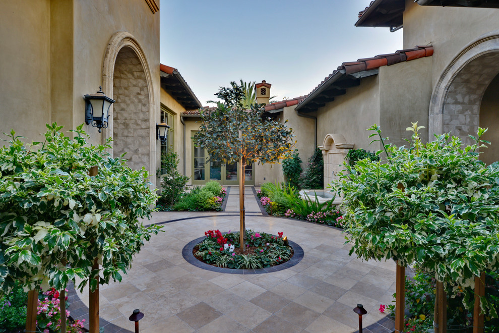 This is an example of a mid-sized mediterranean courtyard patio in San Diego with a container garden, tile and no cover.