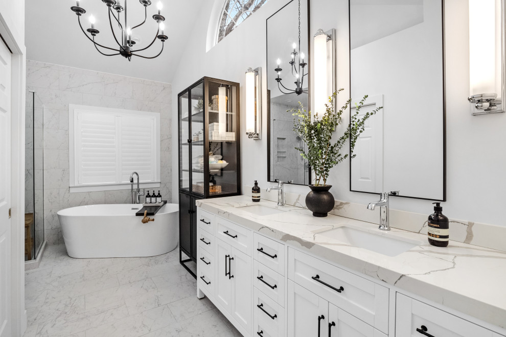 Mid-sized transitional master bathroom in St Louis with white cabinets, a freestanding tub, a corner shower, white tile, grey walls, porcelain floors, an undermount sink, engineered quartz benchtops, white floor, a hinged shower door, white benchtops, a niche, a double vanity, a freestanding vanity, vaulted and shaker cabinets.