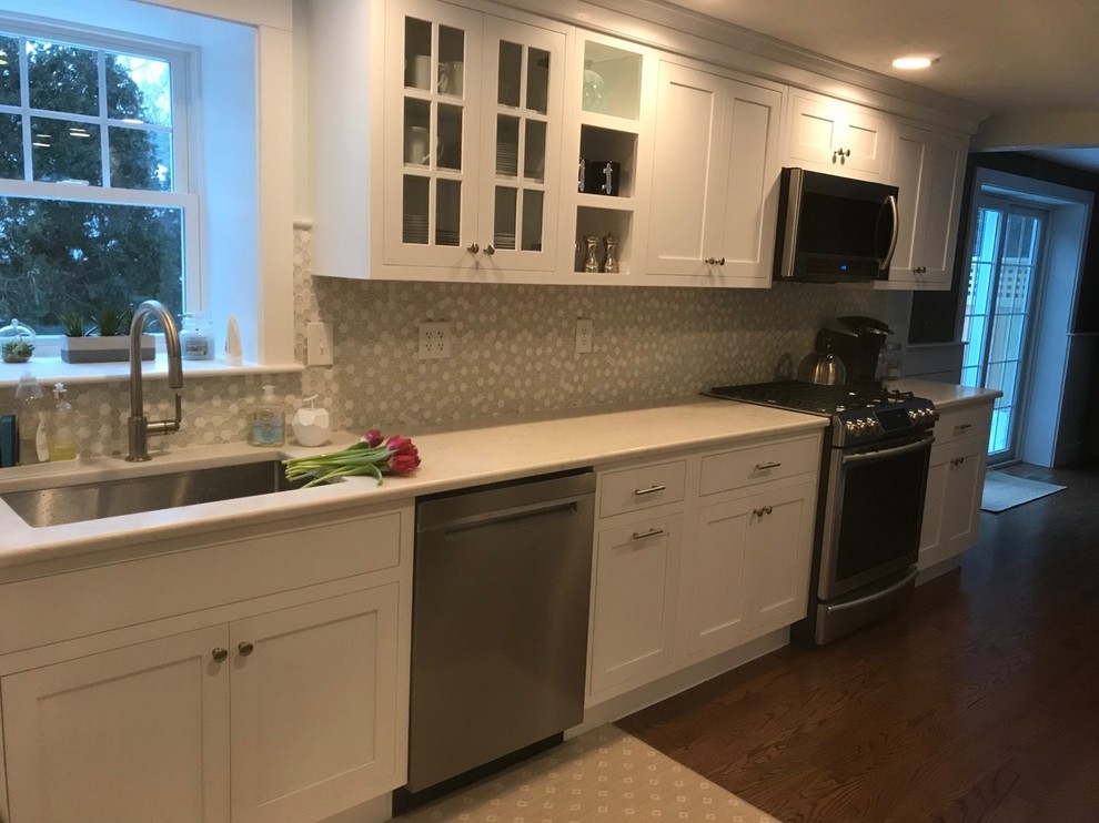 Photo of a mid-sized transitional eat-in kitchen in Boston with an undermount sink, shaker cabinets, white cabinets, grey splashback, stainless steel appliances, dark hardwood floors, no island and brown floor.