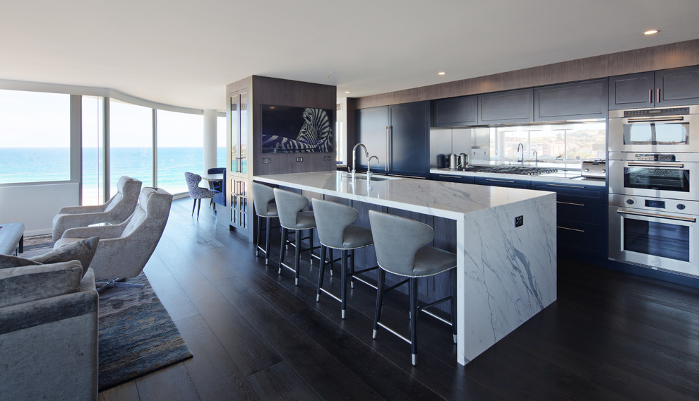 Inspiration for a large contemporary galley dark wood floor and black floor open concept kitchen remodel in Sydney with an undermount sink, shaker cabinets, blue cabinets, marble countertops, mirror backsplash, stainless steel appliances and an island