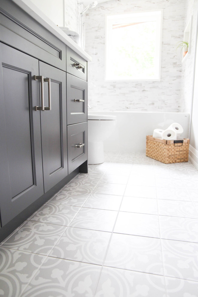 Inspiration for a mid-sized transitional master bathroom in Toronto with shaker cabinets, grey cabinets, a drop-in tub, a shower/bathtub combo, white tile, marble, grey walls, cement tiles, an undermount sink, quartzite benchtops, grey floor, a shower curtain and white benchtops.