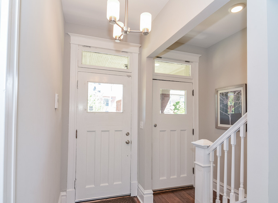 This is an example of a mid-sized transitional front door in St Louis with a double front door, grey walls, dark hardwood floors and a white front door.