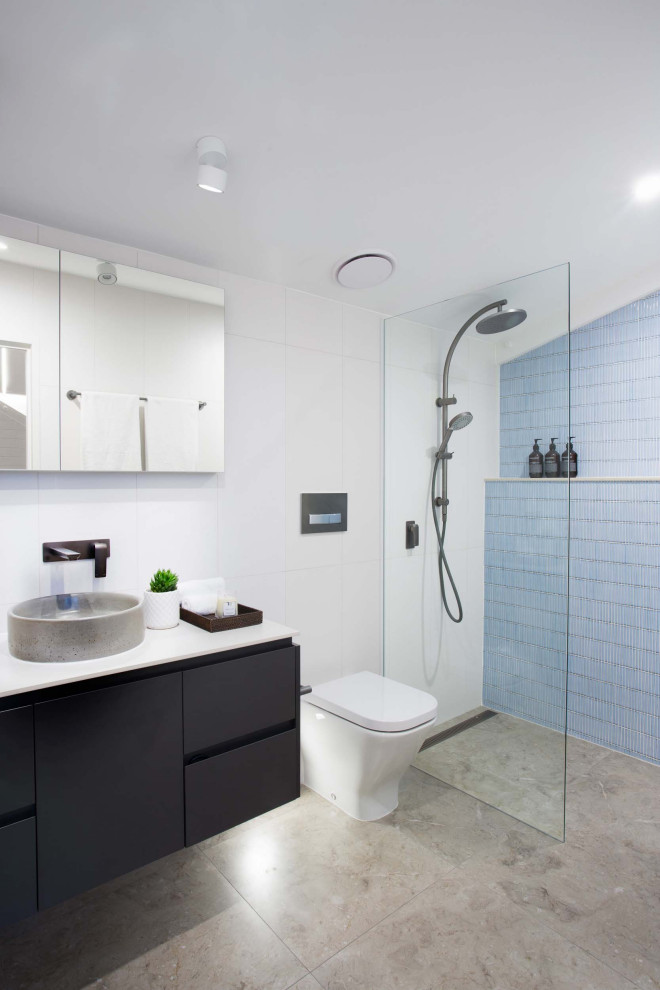 Kleines Industrial Badezimmer En Suite mit flächenbündigen Schrankfronten, grauen Schränken, offener Dusche, Toilette mit Aufsatzspülkasten, blauen Fliesen, Keramikfliesen, weißer Wandfarbe, Keramikboden, Aufsatzwaschbecken, Mineralwerkstoff-Waschtisch, braunem Boden, offener Dusche, weißer Waschtischplatte und schwebendem Waschtisch in Brisbane