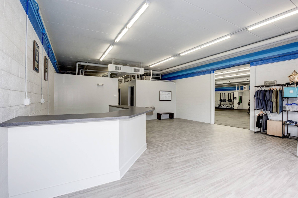 Photo of an expansive industrial multi-use home gym in DC Metro with white walls, cork flooring and black floors.