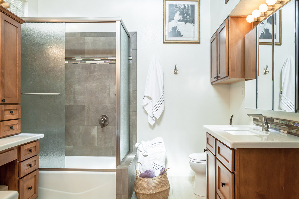 Large transitional master brown tile and porcelain tile porcelain tile and beige floor corner bathtub photo in Phoenix with recessed-panel cabinets, medium tone wood cabinets, a one-piece toilet, beige walls, an undermount sink and quartz countertops