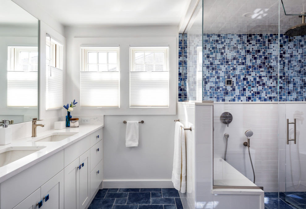 This is an example of a transitional bathroom in Boston with shaker cabinets, white cabinets, a corner shower, blue tile, white tile, white walls, an undermount sink, blue floor, a hinged shower door, white benchtops, a shower seat, a double vanity and a built-in vanity.