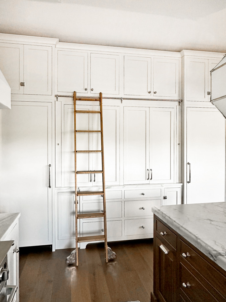 Inspiration for a large transitional u-shaped medium tone wood floor and brown floor kitchen remodel with a drop-in sink, shaker cabinets, white cabinets, marble countertops, white backsplash, marble backsplash, stainless steel appliances, an island and white countertops