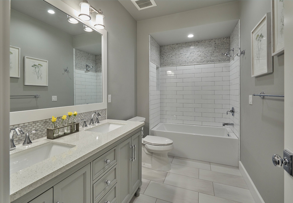 This is an example of a mid-sized arts and crafts kids bathroom in Portland with shaker cabinets, white cabinets, a shower/bathtub combo, a one-piece toilet, multi-coloured tile, glass tile, grey walls, porcelain floors, an undermount sink and grey floor.