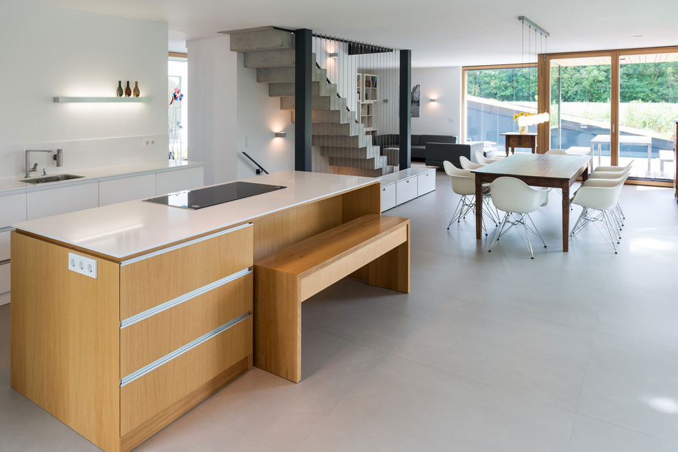 Large contemporary open plan kitchen in Munich with flat-panel cabinets, white cabinets, with island, an undermount sink, white splashback and concrete floors.