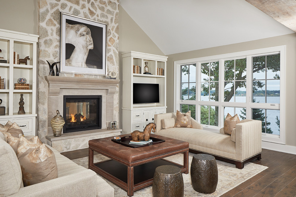 This is an example of a mid-sized eclectic open concept living room in Grand Rapids with beige walls, medium hardwood floors, a two-sided fireplace, a stone fireplace surround and a built-in media wall.