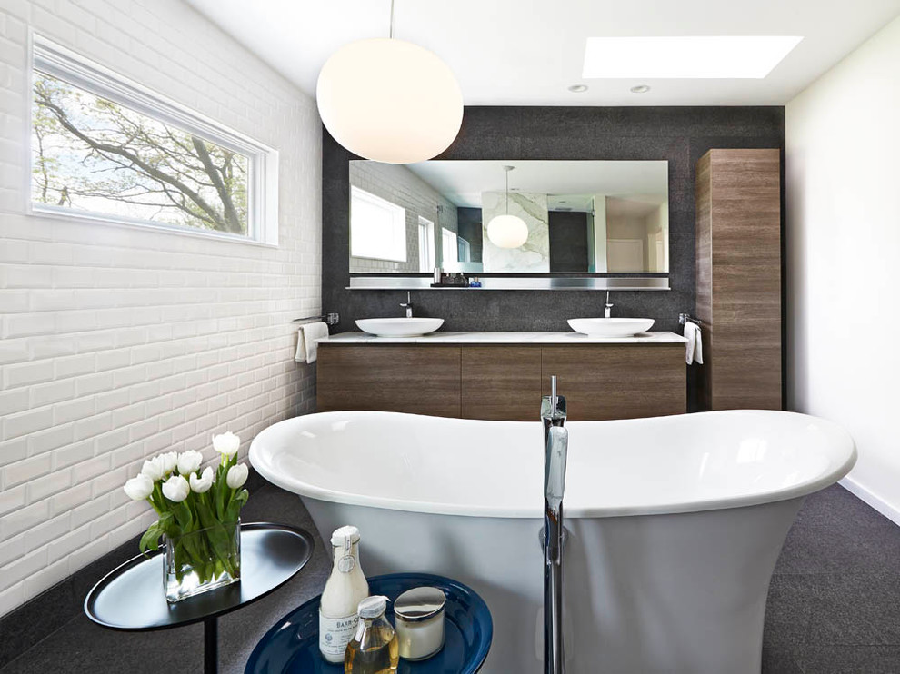 This is an example of a large contemporary master bathroom in Detroit with a vessel sink, flat-panel cabinets, medium wood cabinets, engineered quartz benchtops, a freestanding tub, white tile, ceramic tile, white walls and ceramic floors.
