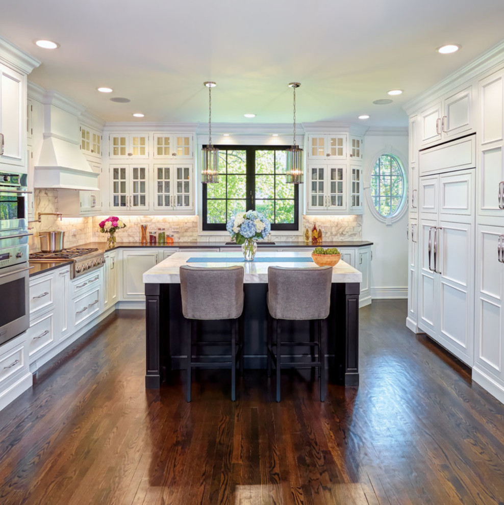 Inspiration for a transitional u-shaped kitchen in Detroit with an undermount sink, recessed-panel cabinets, white cabinets, white splashback, stainless steel appliances, dark hardwood floors, with island, brown floor and white benchtop.