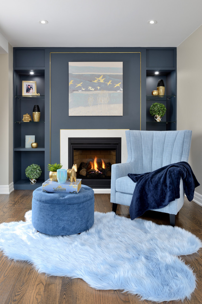トロントにあるおしゃれなファミリールーム (青い壁、無垢フローリング、標準型暖炉、金属の暖炉まわり、茶色い床) の写真