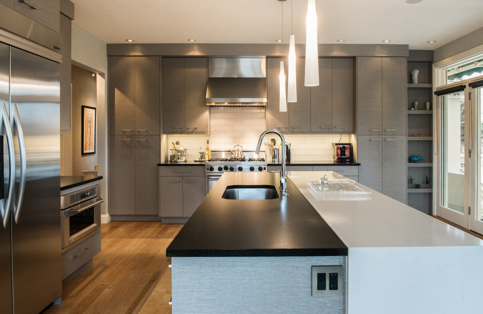 Inspiration for a mid-sized contemporary l-shaped eat-in kitchen in Other with an undermount sink, grey cabinets, quartz benchtops, white splashback, glass tile splashback, stainless steel appliances, with island, flat-panel cabinets, light hardwood floors and beige floor.