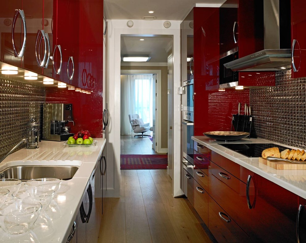 Contemporary galley separate kitchen in London with an undermount sink, flat-panel cabinets, red cabinets and metal splashback.