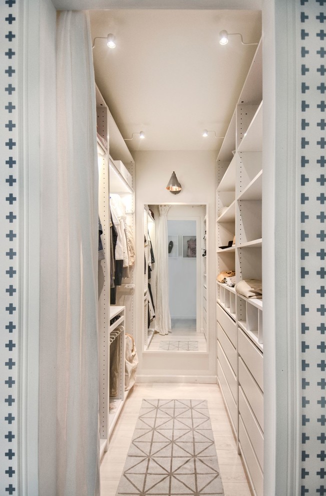 Small scandinavian gender-neutral walk-in wardrobe in Saint Petersburg with white cabinets, laminate floors, flat-panel cabinets and beige floor.